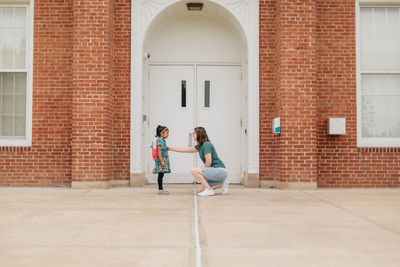 Young millennial mother sending daughter off back to school