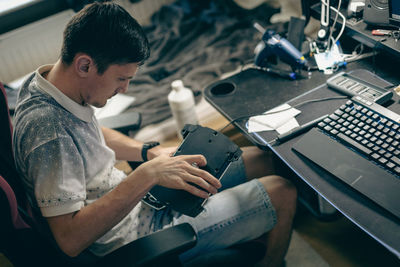 A young man repairs the engine steering wheel on a joystick.