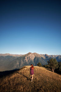 Man standing on mountain against clear blue sky