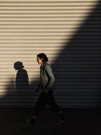 Side view of young woman standing against wall