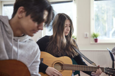 Teenagers attending guitar lesson