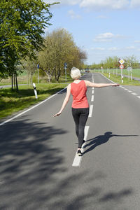 Rear view of woman walking on road against sky