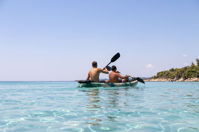 Happy two teenagers kayaking together in amazing clear water of aegean family adventures concept