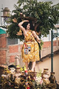 Woman standing by statue against plants