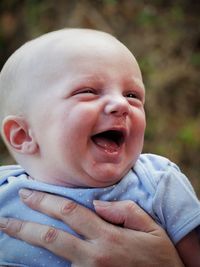 Cropped hands of mother holding cute happy baby boy