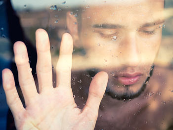 Close-up of hand on wet window