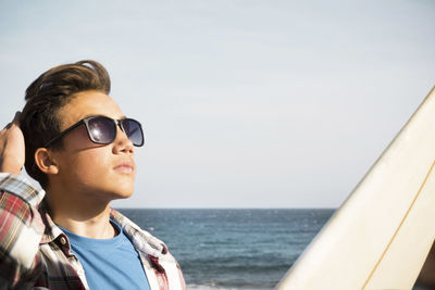 Portrait of man wearing sunglasses against sea against sky