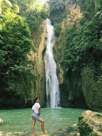 Rear view of woman standing in waterfall