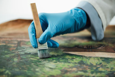 Restoring old oil painting, conservator removing varnish from an oil painting