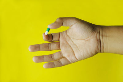 Close-up of human hand against yellow background