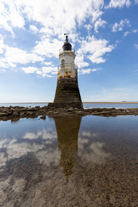 Lighthouse by sea against sky