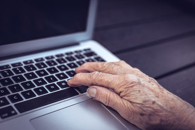 Old persons hand on laptop keyboard