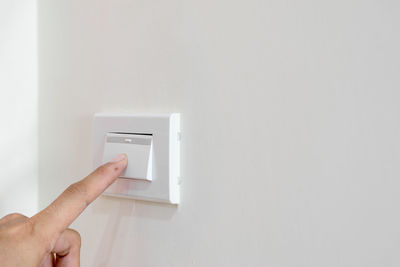 Cropped hand pressing button on wall at home