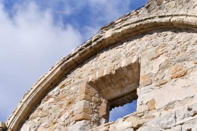 Low angle view of old ruin building against cloudy sky