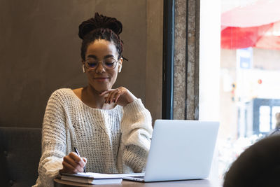 Young woman using phone while sitting on table