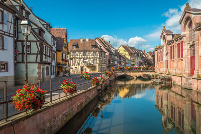 Canal amidst buildings against blue sky