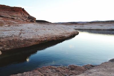 Scenic view of lake by rock formation against clear sky