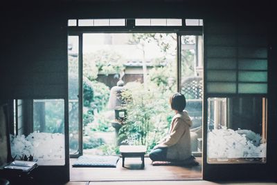 Side view of woman sitting in glass window