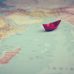 Close-up of red paper boat on map