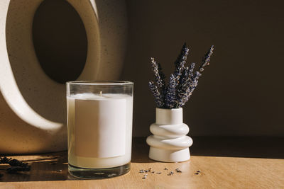 Natural wax candle with empty label and small vase with lavender flowers. candle label mock-up. 