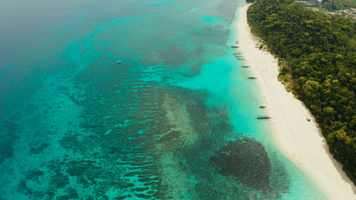 Travel concept sand beach with tourists and turquoise water on boracay, philippines, aerial drone.