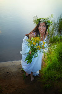 Portrait of young woman standing against plants