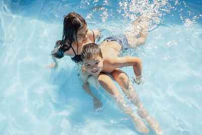 Joyful scene captures a brother and sister playing, blue pool, embodying the spirit of summer fun