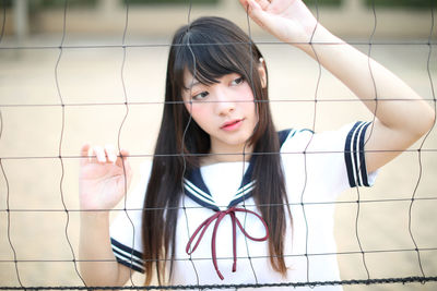 Young woman standing by sports net