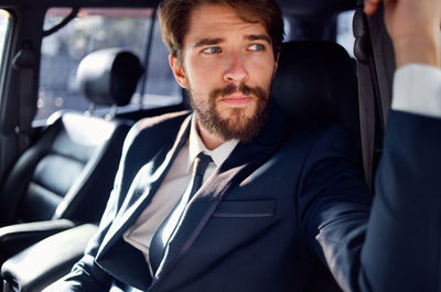 Businessman sitting in car while looking away