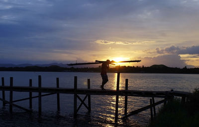 Silhouette man standing by sea against sky during sunset