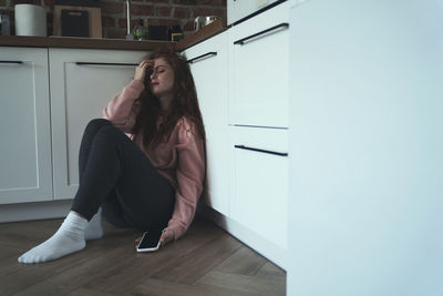 Portrait of young woman standing against wall