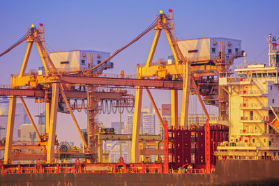 Cranes at commercial dock against clear sky