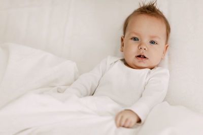 Portrait of cute baby lying on bed at home