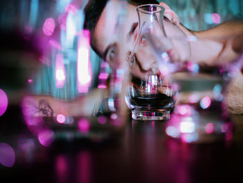 Portrait of young man lying on table seen through drinking glass at home