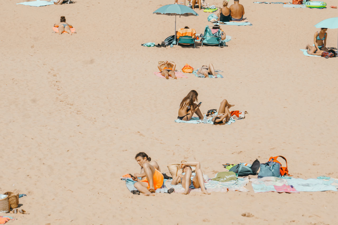 HIGH ANGLE VIEW OF PEOPLE SITTING AT BEACH