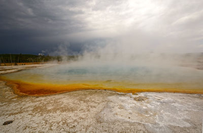 Storm clouds over sapphire pool in biscuit basin in yellowstone national park in wyoming