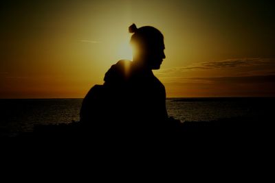 Silhouette man standing at beach during sunset