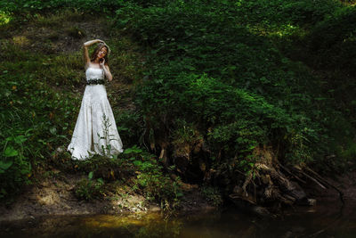 Beautiful woman in white dress standing at lakeshore