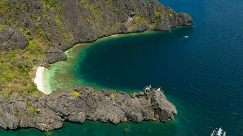 Aerial view tropical lagoon with sandy beach surrounded by cliffs. el nido, philippines, palawan. 