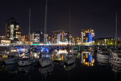 Boats moored in harbor at night