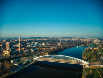 High angle view of river amidst buildings against clear blue sky