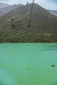 Overhead cable car over sea against mountains