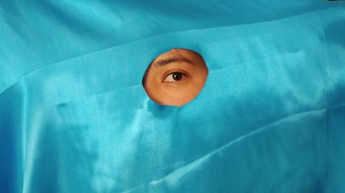 Portrait of person looking through hole in satin