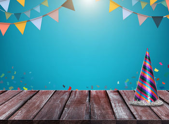 Digital composite image of party hat on table against blue sky