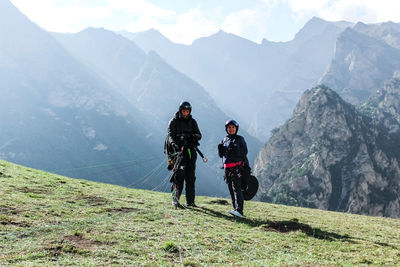 People on mountain top with paragliding equipment