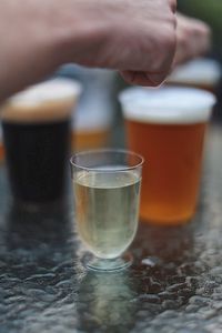 Cropped hand of man with drinks at table in yard