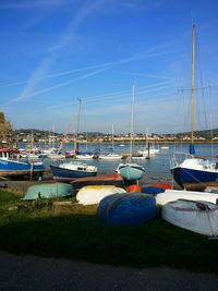 Boats moored at harbor against clear blue sky