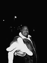 Portrait of man standing against black background