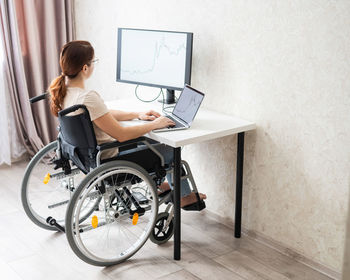 Side view of young woman using laptop at home