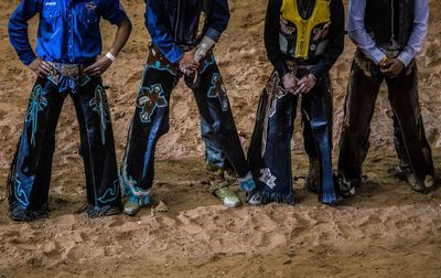 Low section of men wearing costumes standing on sand